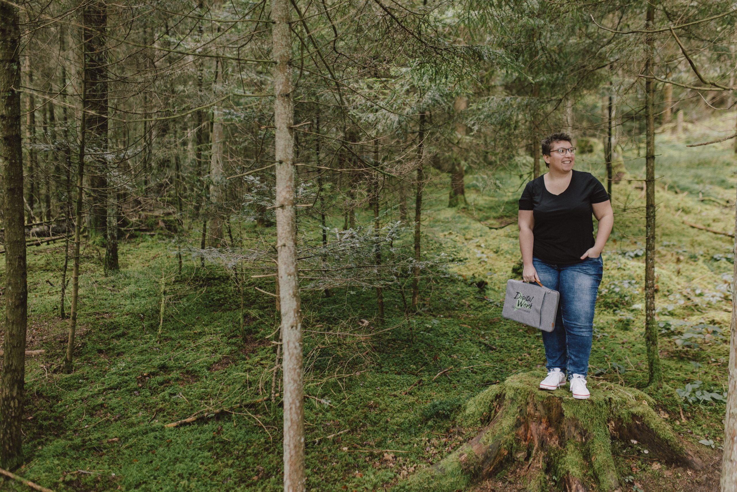 Header_Marketingprojekt-Seite. Die GrĂĽnderin des DigitalWerk Schwarzwald Priscilla Stober auf einem Baumstamm stehend im Wald zu sehen.